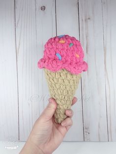 a hand holding an ice cream cone with pink and blue sprinkles on it