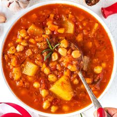 a white bowl filled with stew next to garlic and red pepper on a tablecloth