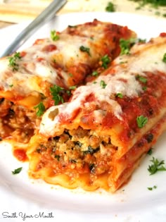 two slices of lasagna on a white plate with a fork and parsley