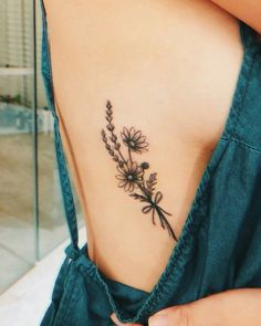 the back of a woman's neck with flowers on her left side and an arrow tattoo