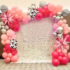 a pink and silver balloon arch with balloons