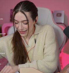 a woman sitting in a chair with headphones on and looking at a book she is reading