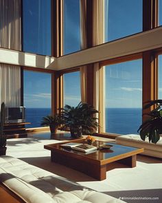 a living room filled with furniture and large windows looking out to the ocean on a sunny day