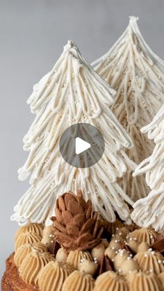 a cake decorated with white icing and pine cones on top of it, surrounded by cookies