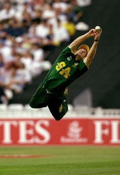 a baseball player catching a ball in mid air with his leg up and arms outstretched