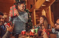 a group of people sitting around a table with christmas presents in front of the camera