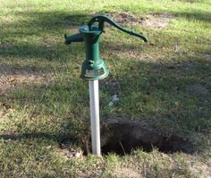 a green fire hydrant sitting in the middle of a field