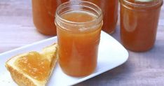 several jars of honey sit on a plate next to a slice of bread and jam