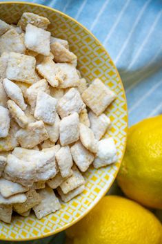 a yellow bowl filled with chunks of food next to lemons on a blue and white table cloth