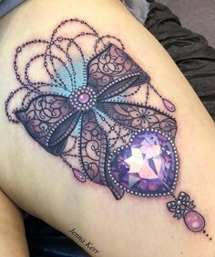 a woman's thigh with an intricate tattoo design on the leg and purple jewel