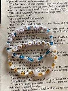 two bracelets with words written on them sitting next to an open page of a book