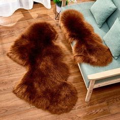 two brown fur rugs sitting on top of a wooden floor next to a blue couch