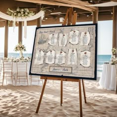 an easel with seating cards on it in front of a beach wedding venue at the ocean