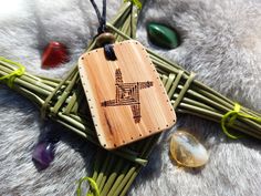 a wooden pendant with an image of a cross on it next to some rocks and plants