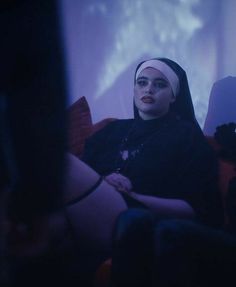 a woman sitting on top of a couch in front of a projection screen wearing a headscarf