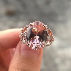 someone is holding an oval shaped pink diamond in their hand