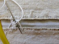 a pair of scissors and thread on top of a piece of fabric with stitching