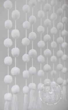 white pom - poms hanging from the ceiling in front of a gray background