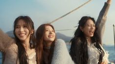 three young women standing next to each other with their arms in the air and smiling