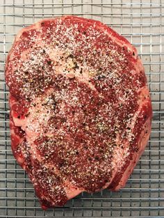 a piece of meat sitting on top of a metal grill grate covered in seasoning