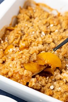 a white dish filled with oatmeal topped with peaches and granola