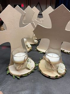 two tea cups and saucers on wooden coasters with white roses tied around them