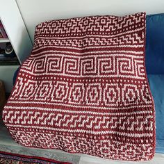 a red and white blanket sitting on top of a blue couch next to a book shelf