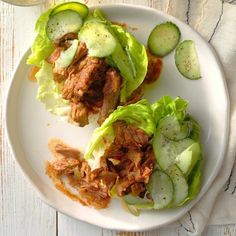 two lettuce wraps with meat and cucumber slices on a white plate