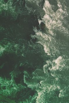 an aerial view of the ocean waves and surfers