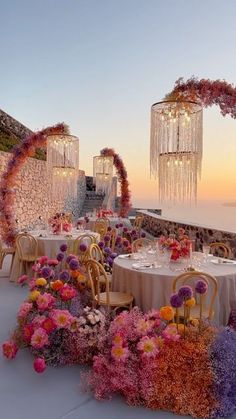 an outdoor dining area with flowers and chandelier hanging from the ceiling at sunset