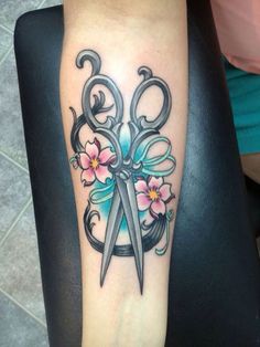 a tattoo with scissors and flowers on it