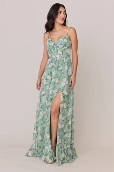 a woman wearing a green and white floral print dress with thigh high slit, side view