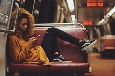 a woman sitting on a train looking at her phone