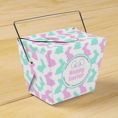 a pink, blue and green box with the words happy easter on it sitting on a wooden surface