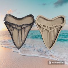 two heart shaped boxes sitting on top of a sandy beach