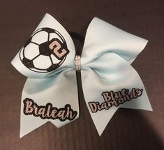 "Soccer Bow and Soccer gifts offered at Xtreme BoWtique. We specialize in Soccer Bows to match with a cute shirt or soccer uniform. Order soccer bows for the whole team. Approx 7\" across 3\" wide base ribbon Attached to pony o band All Handmade in the USA. How to Order your custom volleyball bow Add Your Quantity to the Cart Proceed to checkout In optional notes Ribbon Color Volleyball color Number or Name Orders ship out 3-7 days M-F Team Orders ship 5-14 days Bulk Orders Ship Priority Mail Pl Soccer Ribbon, Soccer Hair Bows, Soccer Crafts, Softball Hair Bows, Volleyball Bows, Soccer Bow, Pit Crew Shirts, Girls Soccer Team, Soccer Team Gifts