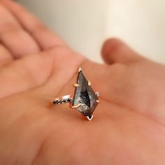 a woman's hand holding an engagement ring with a black diamond in the middle