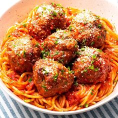 spaghetti and meatballs in a white bowl with parsley on the side, ready to be eaten