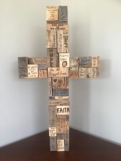 a cross made out of wine corks sitting on top of a wooden table next to a wall