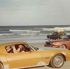 two cars parked on the beach next to each other with people in the back seat