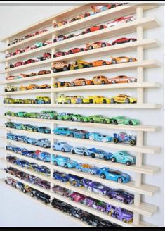 a white wall mounted shelf filled with lots of toy cars