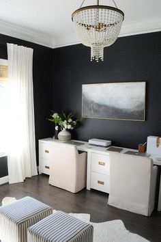 a living room with black walls, white furniture and a chandelier hanging from the ceiling