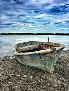 an old boat is sitting on the shore