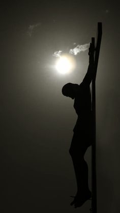 a man climbing up the side of a pole on top of a street sign with the sun in the background