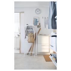 a white room with a coat rack, clock and clothes hanging on the door hangers