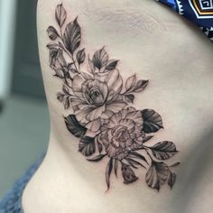 a woman's lower back tattoo with flowers on her stomach and leaves in the middle