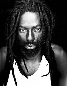 a black and white photo of a man with dreadlocks