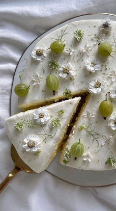 a cake with white flowers and green olives on it is sitting on a plate