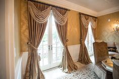 a living room filled with furniture next to a window covered in curtains and drapes