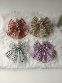 four different colored bows with pearls hanging from them on a white furnishing surface